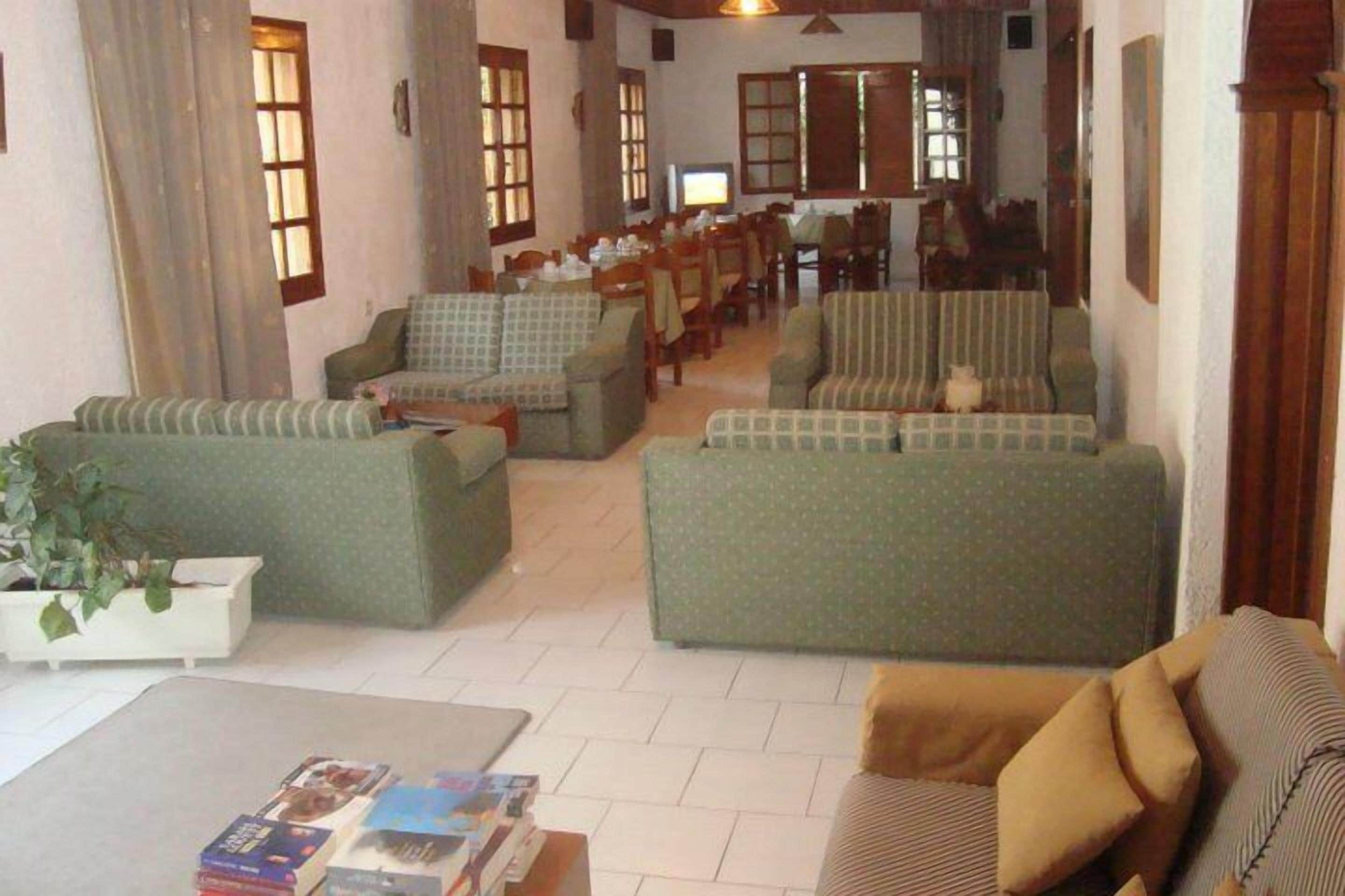 A spacious living area with multiple sofas and armchairs, a dining table, and a television.