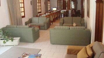 A spacious living area with multiple sofas and armchairs, a dining table, and a television.