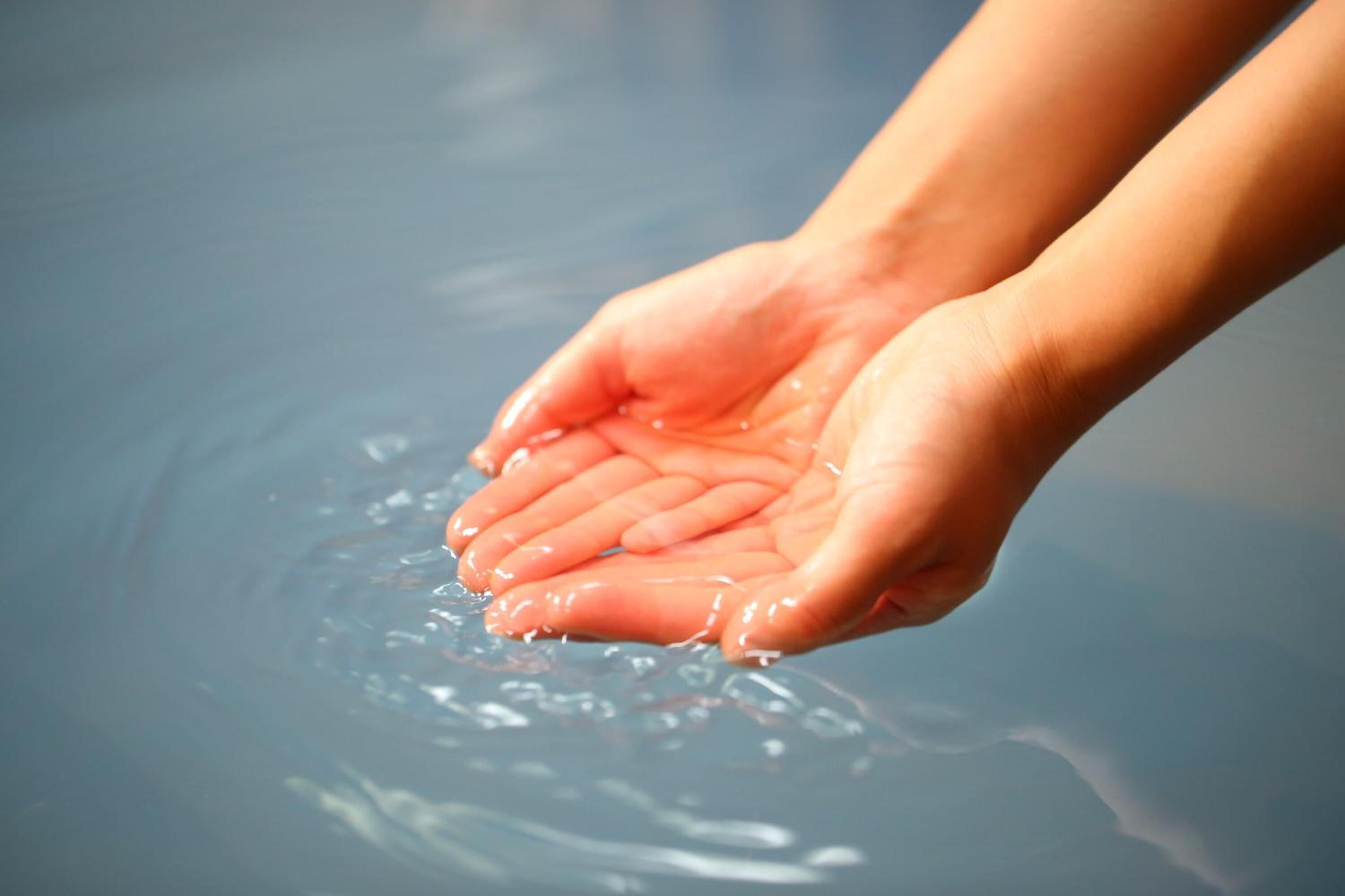 A pair of hands cupped over a body of water.