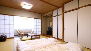 A traditional Japanese-style room with tatami flooring, a futon bed, sliding doors, and a television. - Hotel Yudanaka (Yamanouchi)