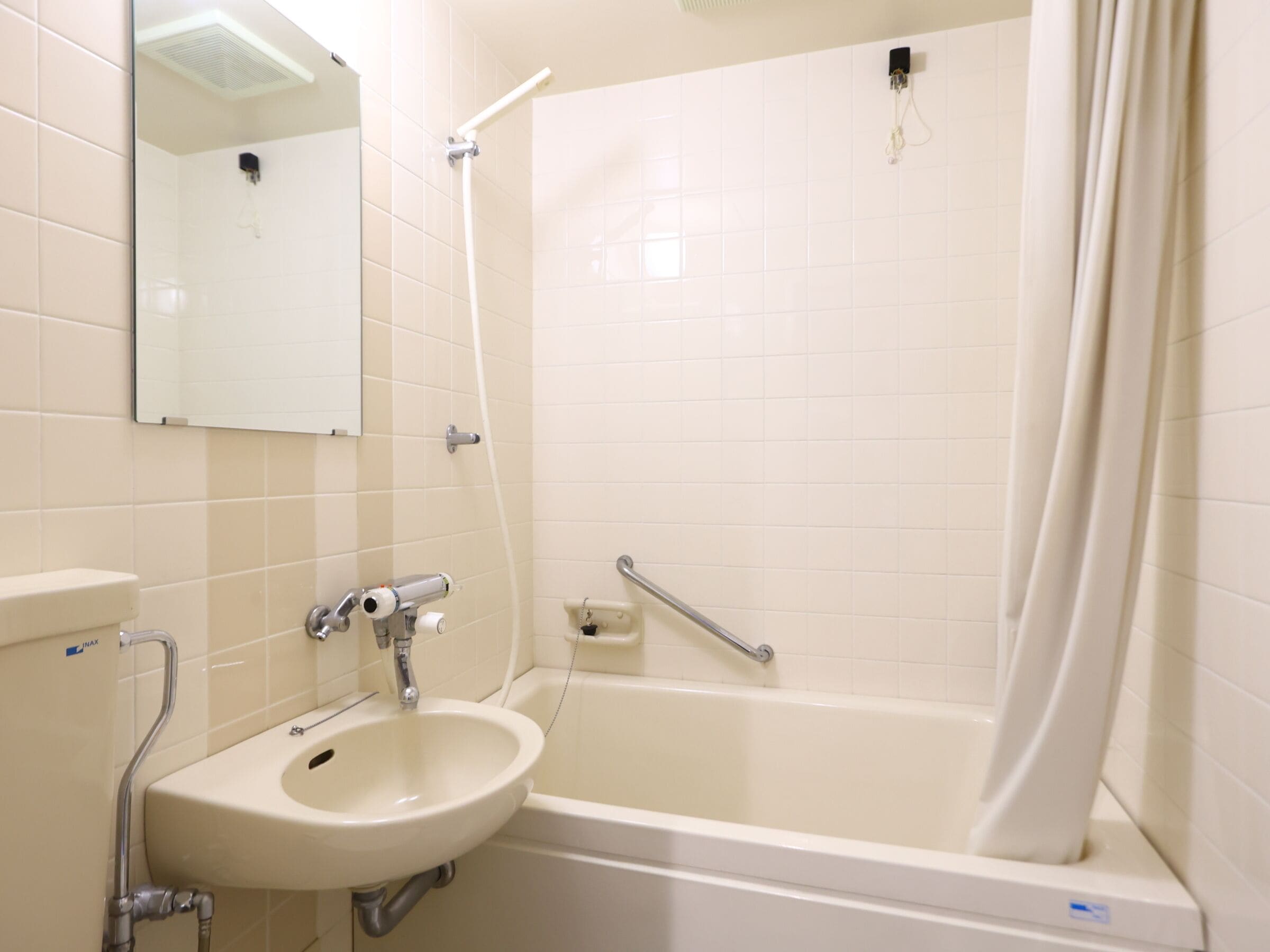A bathroom with a sink, mirror, and bathtub.