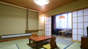 A traditional Japanese room with tatami flooring, a low wooden table, a sliding door, and a ceiling light. - Hotel Yudanaka (Yamanouchi)