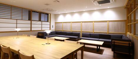 A conference room with a wooden table, chairs, a sofa, and a lamp.