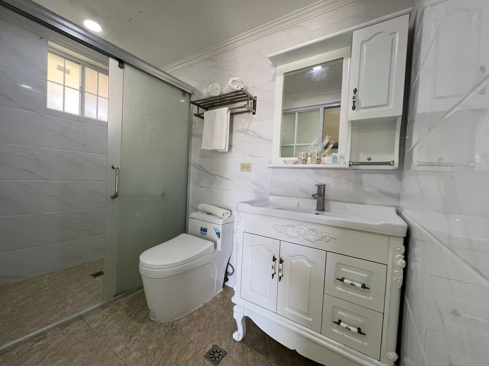 A bathroom with a toilet, a sink with a mirror above it, and a shower area.