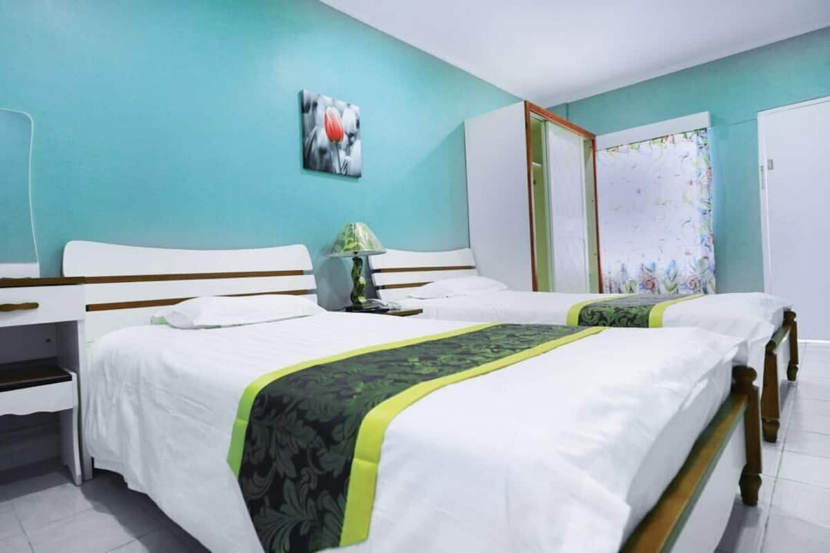 A bedroom with two beds, a desk, and a wardrobe.