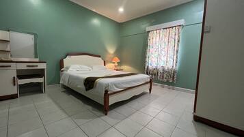 Un dormitorio ordenado con cama, mesita de noche, lámpara y escritorio con cajones.