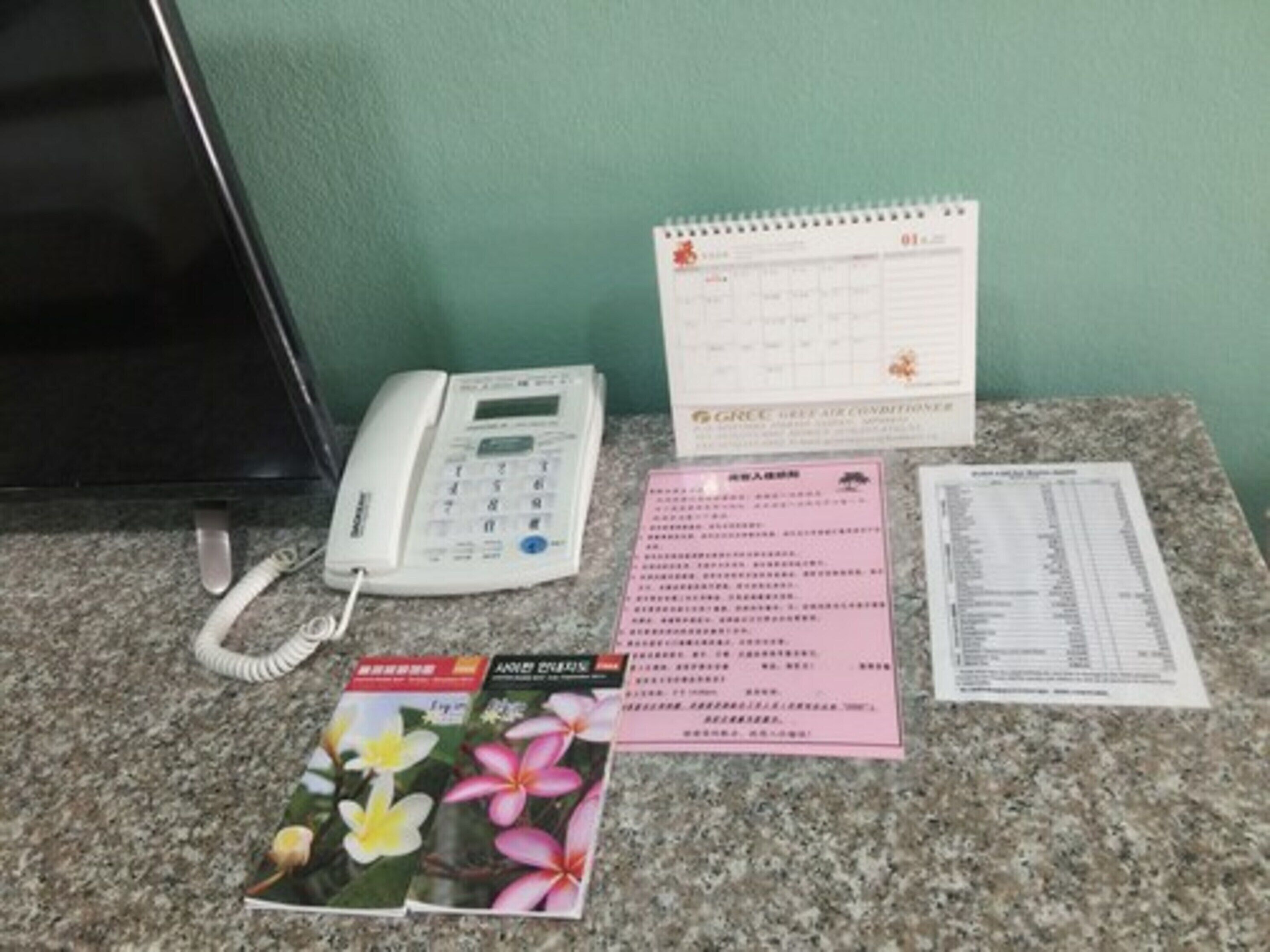A desk with a telephone, a calendar, a menu, and a brochure.