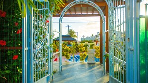 An ornate metal gate leading to a pool area with a clear view of a building in the background. - Beach Garden Hotel (Saipan)