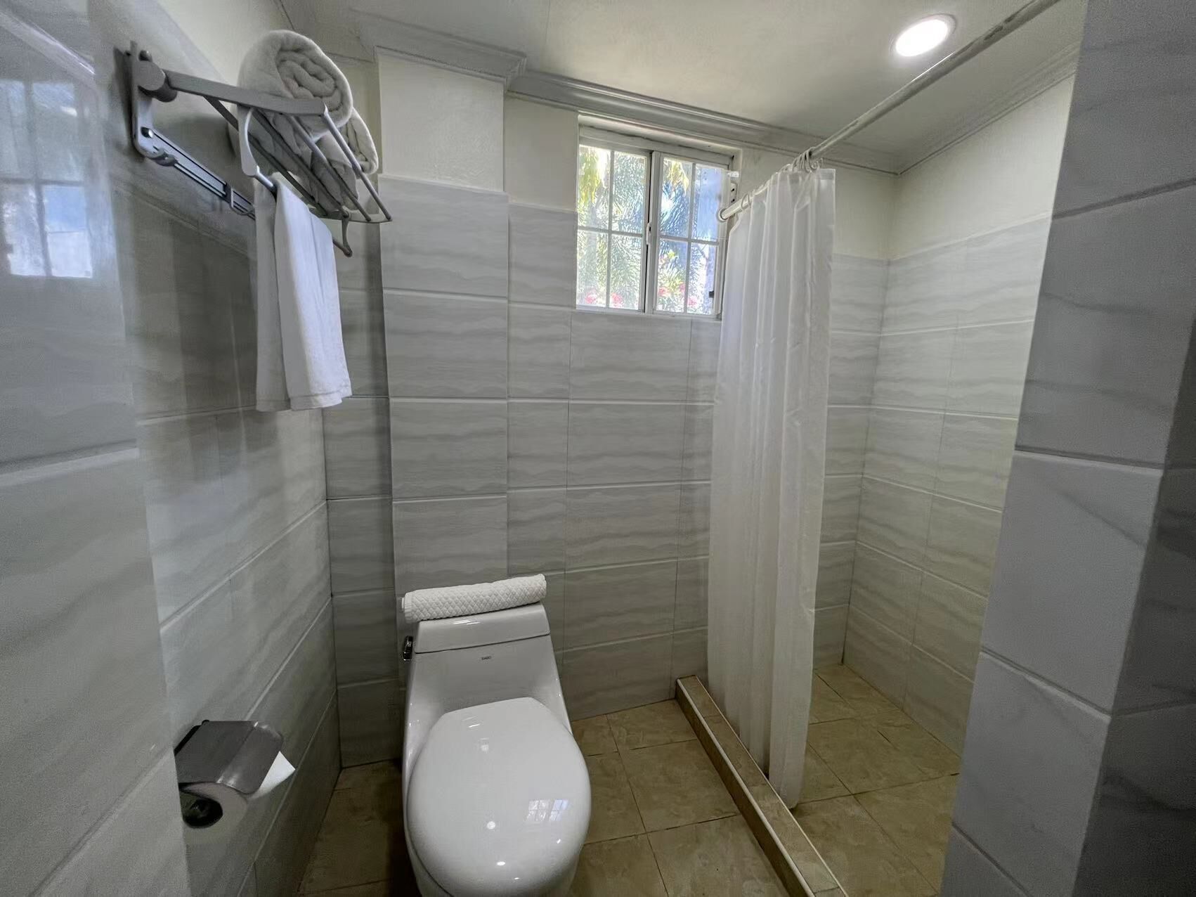 A small, modern bathroom with a toilet, a towel rack, and a shower curtain.