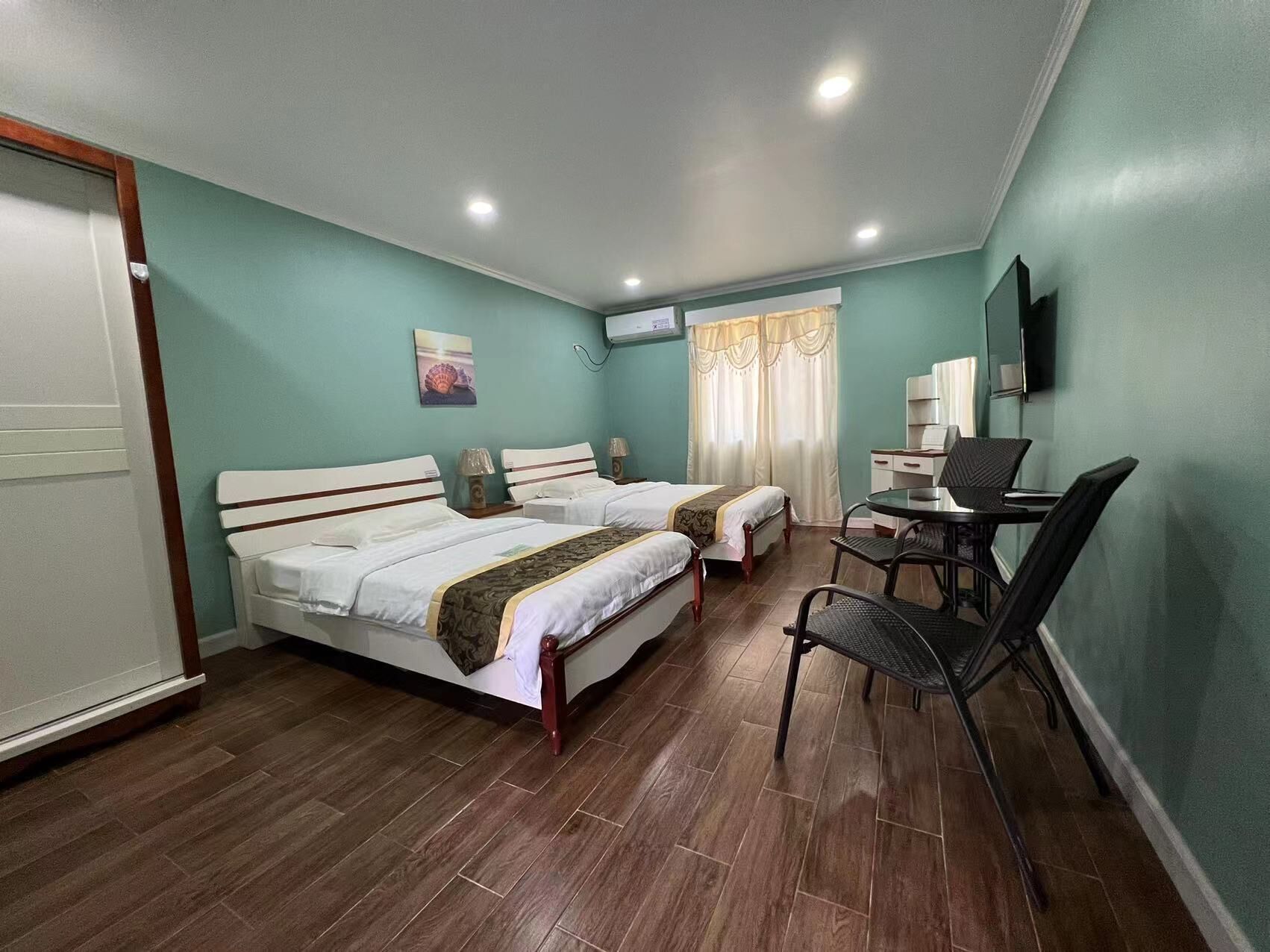 A hotel room with two beds, a desk, a chair, and a television.