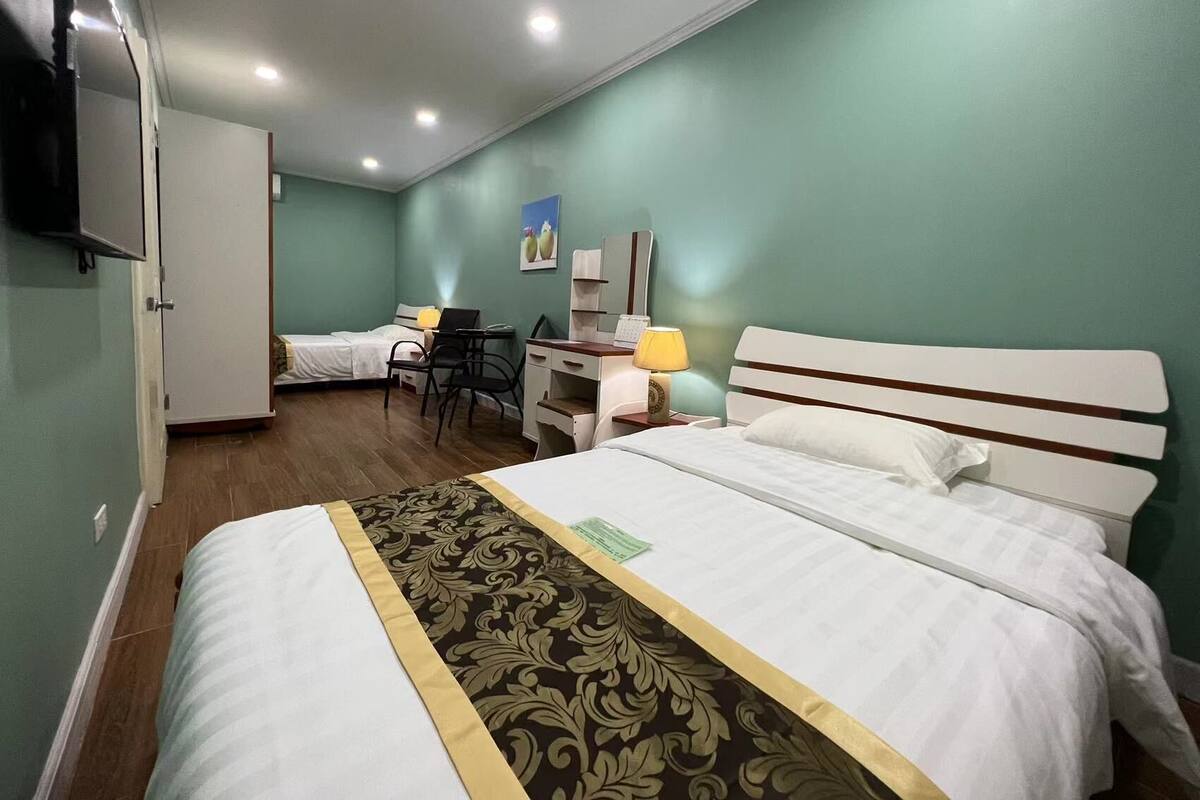 A hotel room with a bed, a desk, a chair, and a wardrobe.