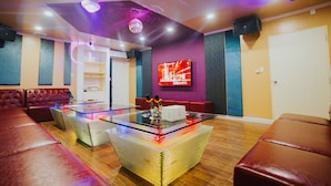 A modern living room with leather sofas, a glass coffee table, and a flat-screen TV mounted on the wall. - Beach Garden Hotel (Saipan)