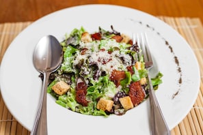 A plate of salad with croutons and grated cheese.