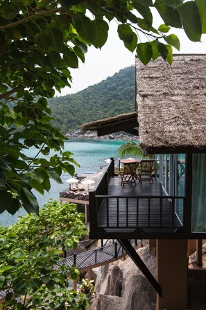 A wooden deck with outdoor furniture overlooking a body of water and a mountainous landscape.