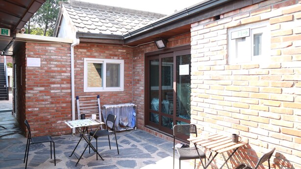 A patio area with a brick building, a table with chairs, and a covered seating area. - 88st GUESTHOUSE Jongno (Seoul)