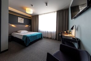 Relax in a clean and functional room with a comfortable bed, desk, and flat-screen TV.
