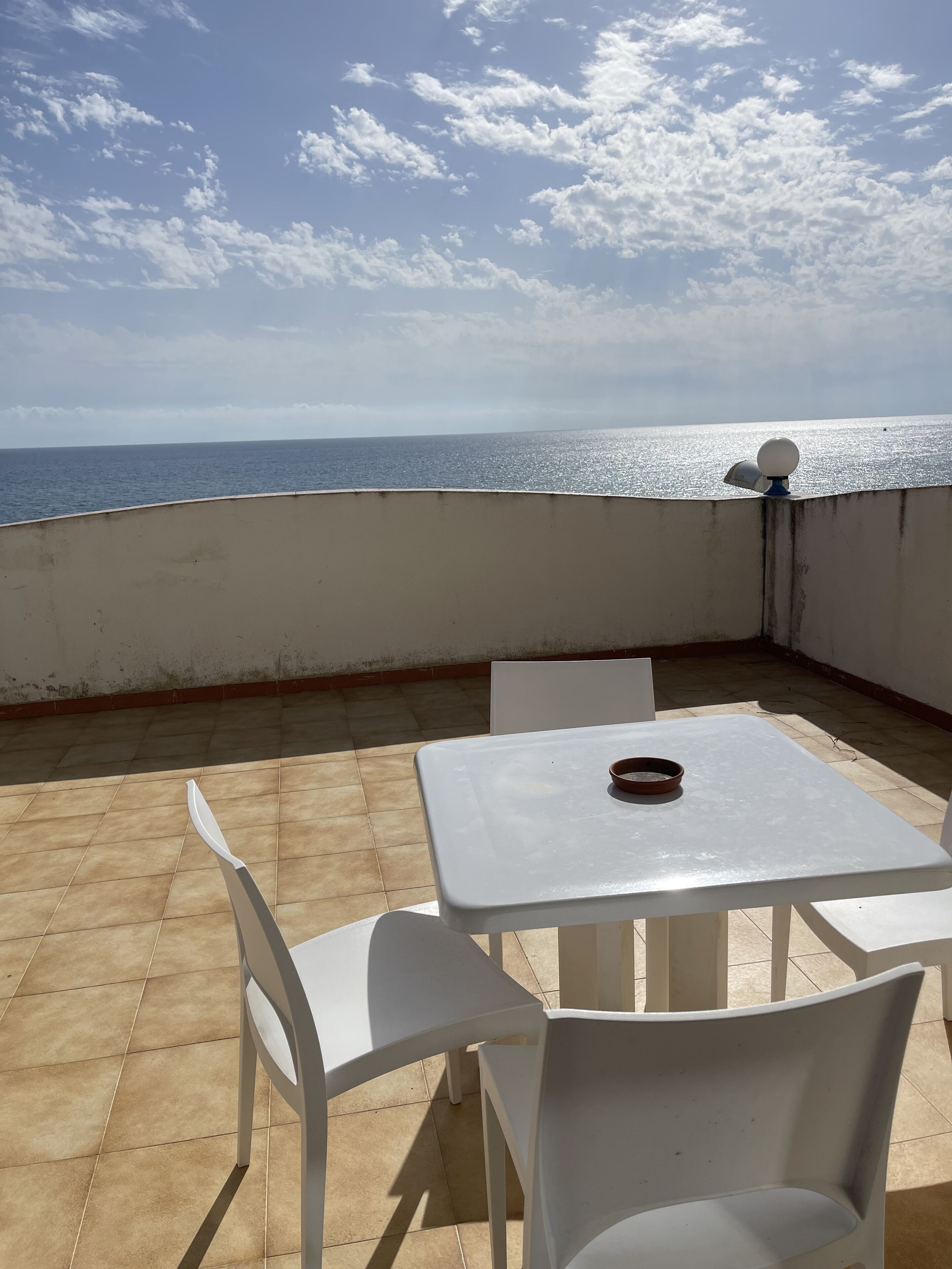 A terrace with a table and chairs, overlooking the sea.