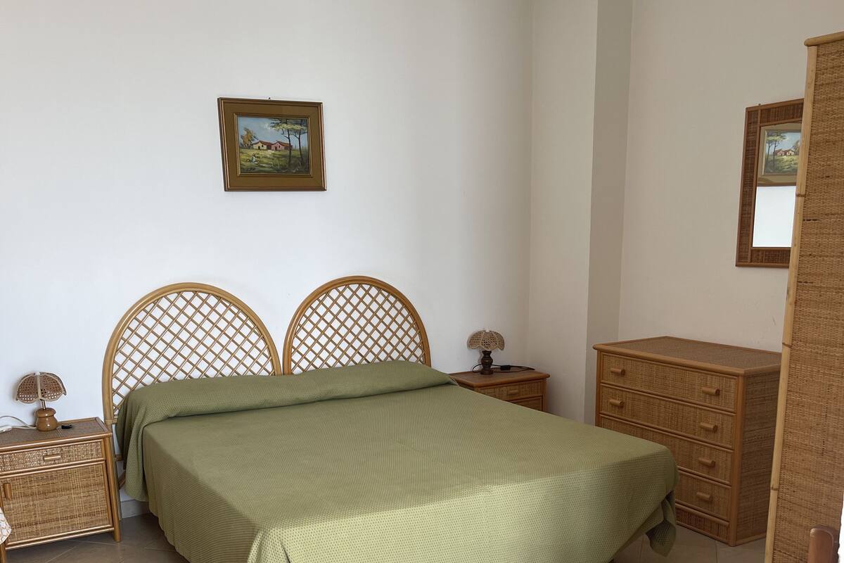 Une chambre à coucher avec un lit, une table de chevet, une commode et une chaise.