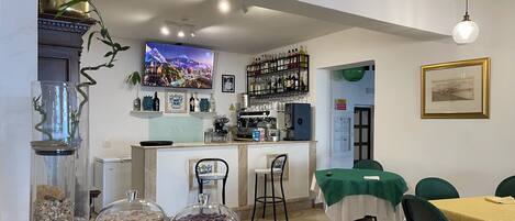 A dining area with a buffet setup, a coffee machine, and a television displaying a cityscape.