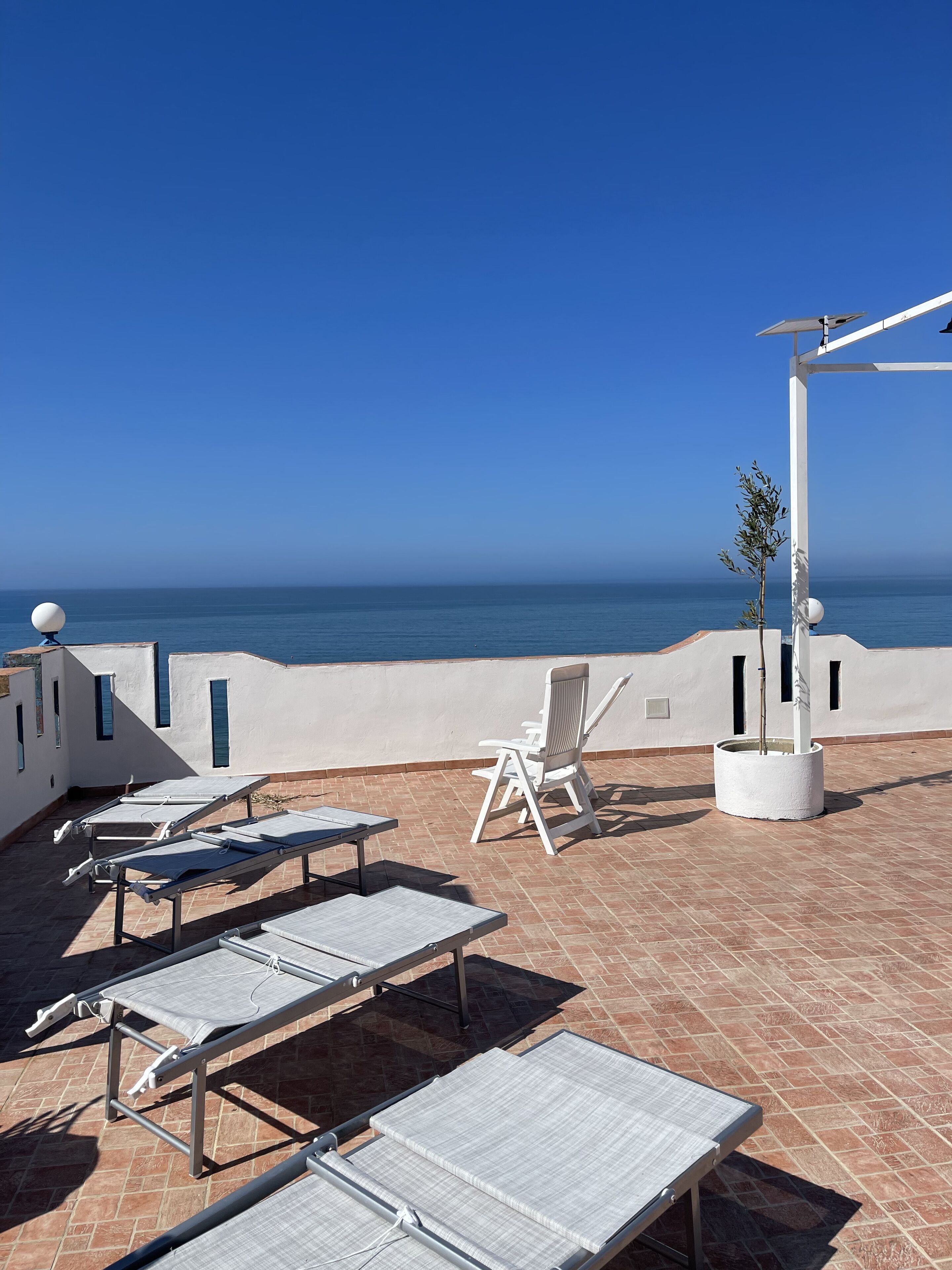 A terrace with sun loungers and a chair overlooking the sea.