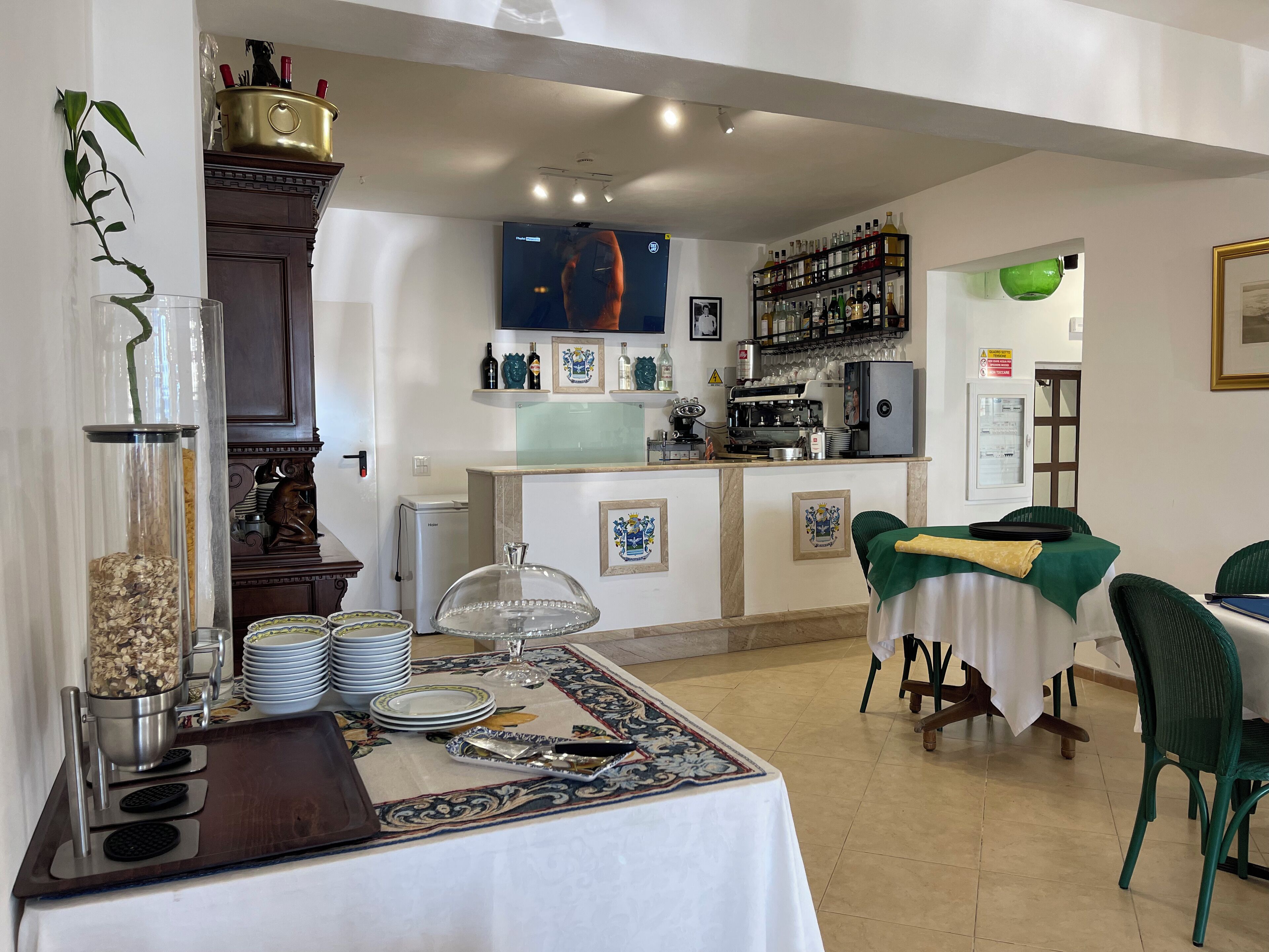 A dining area with a buffet setup, a coffee machine, and a bar area with shelves of bottles.