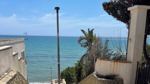 A stone staircase leading to a balcony overlooking a beach with a clear view of the sea. - Hotel Miramare Garzia (Castelvetrano)