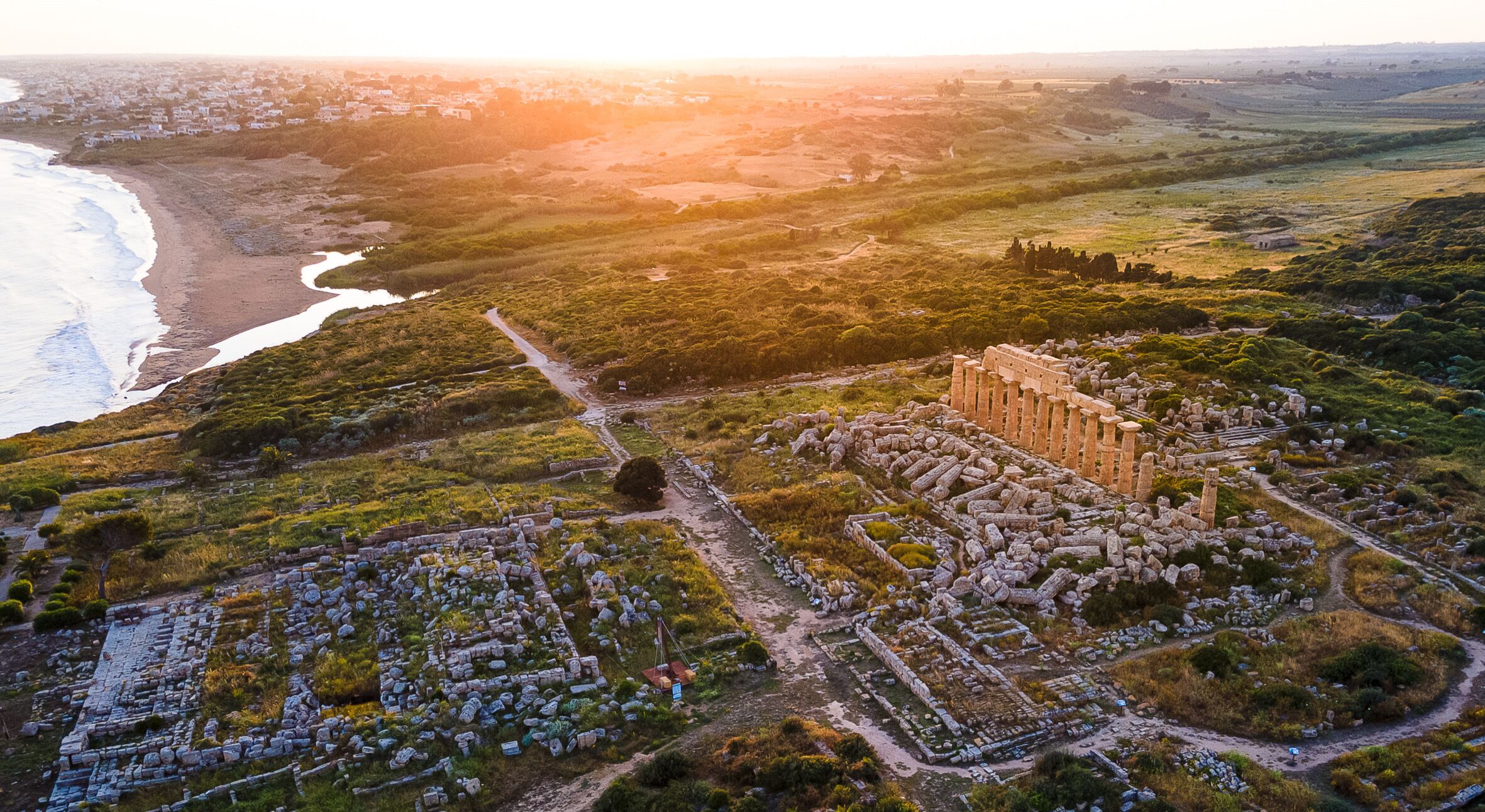 An ancient archaeological site with ruins and a coastal view.