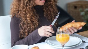 A person sitting at a table with a croissant, a glass of orange juice, and a cup. - City Guesthouse De Rozenboom (Leeuwarden)
