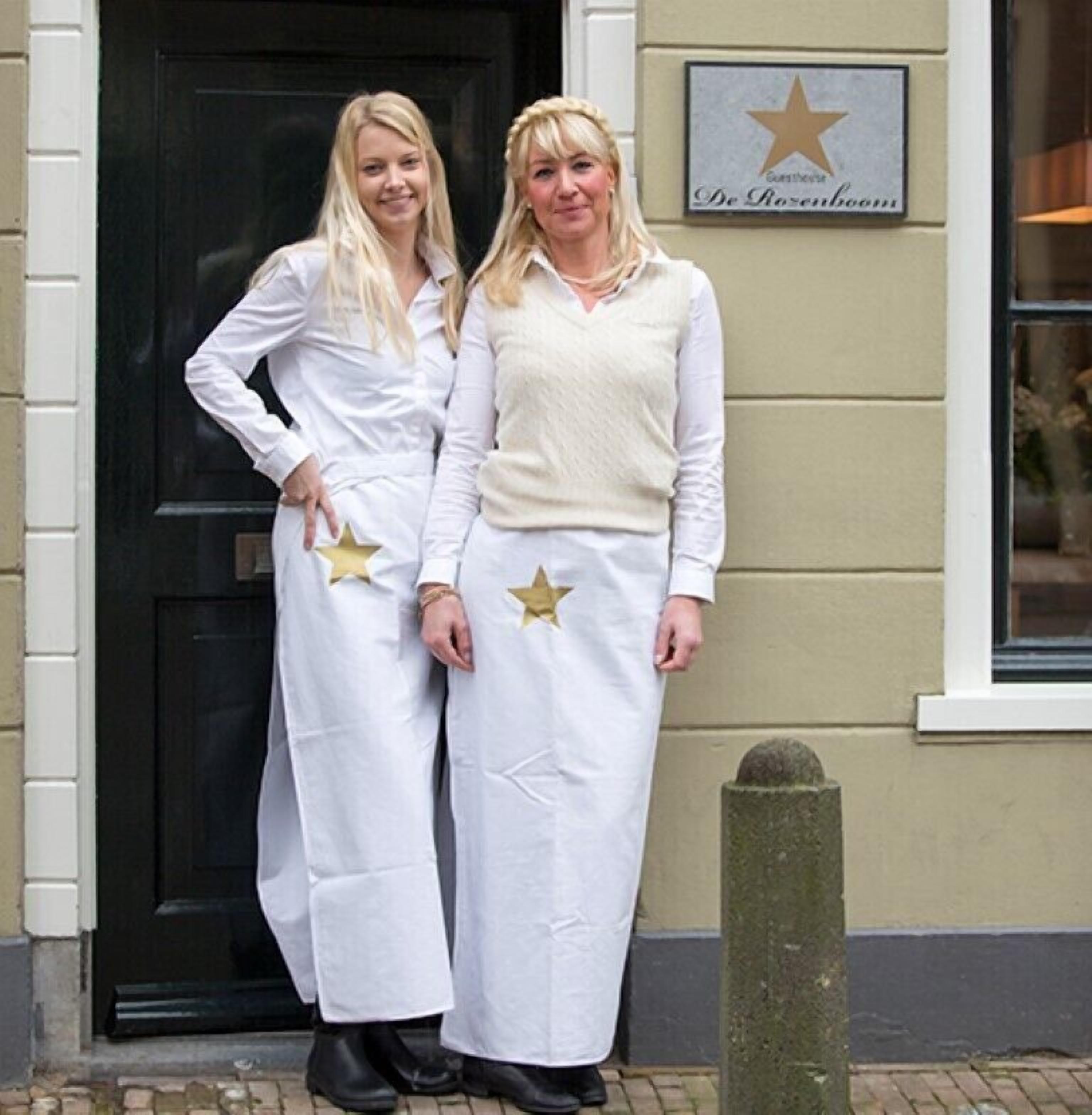 Two individuals in white robes with star decorations standing in front of a building with a black door and a sign above it.