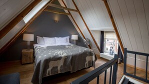 A cozy attic bedroom with a sloped ceiling, a bed with a patterned blanket, two bedside lamps, and a small wooden nightstand. - City Guesthouse De Rozenboom (Leeuwarden)