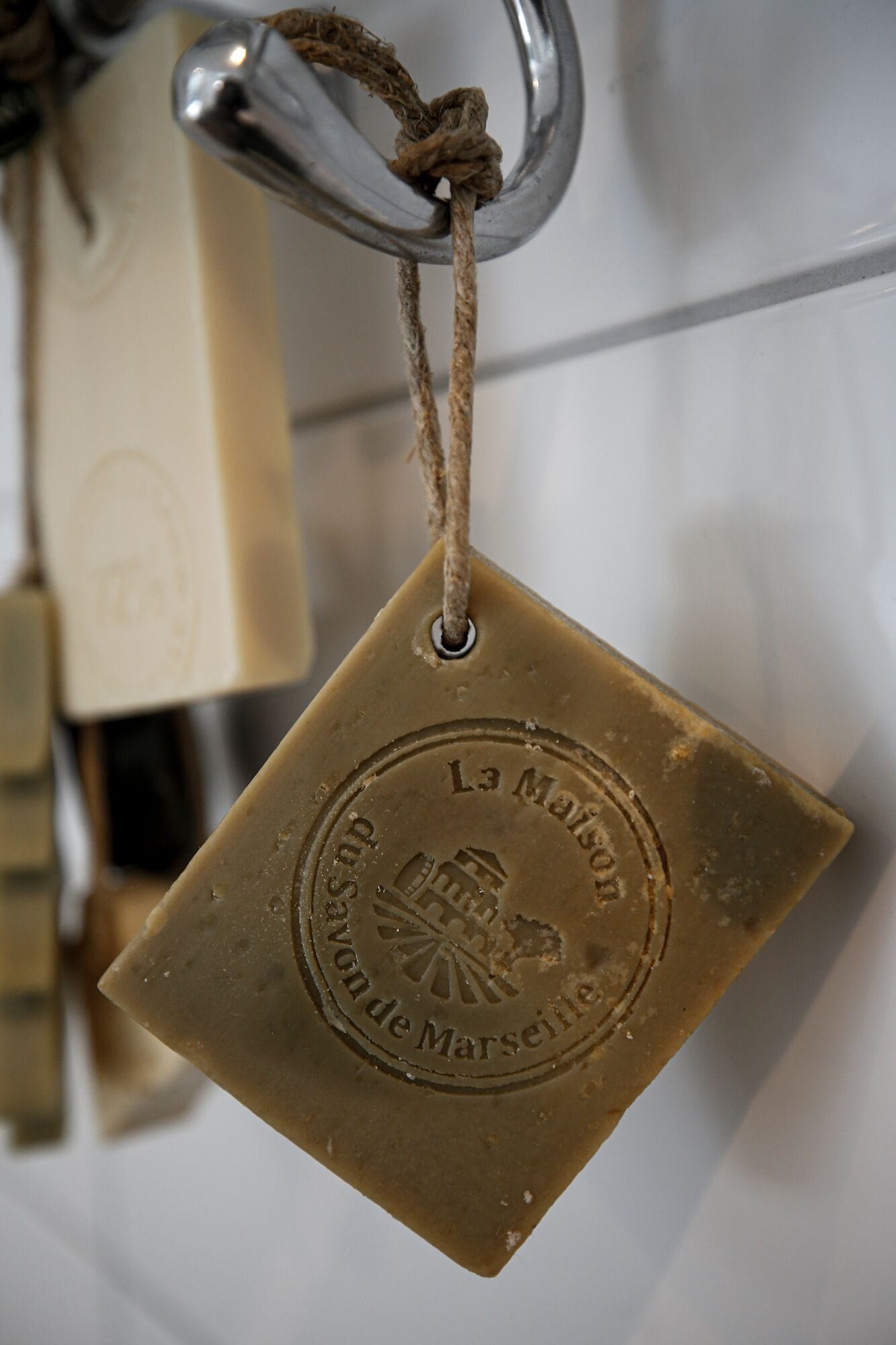 Una saponetta quadrata con una corda legata attorno, appesa a un gancio metallico.