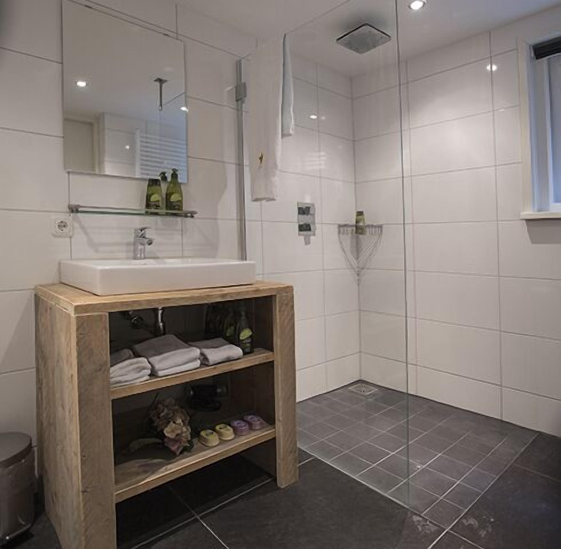 Une salle de bain moderne avec un meuble-lavabo en bois, un grand miroir et un espace douche.