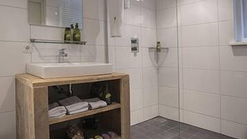 Une salle de bain moderne avec un meuble-lavabo en bois, un grand miroir et un espace douche.