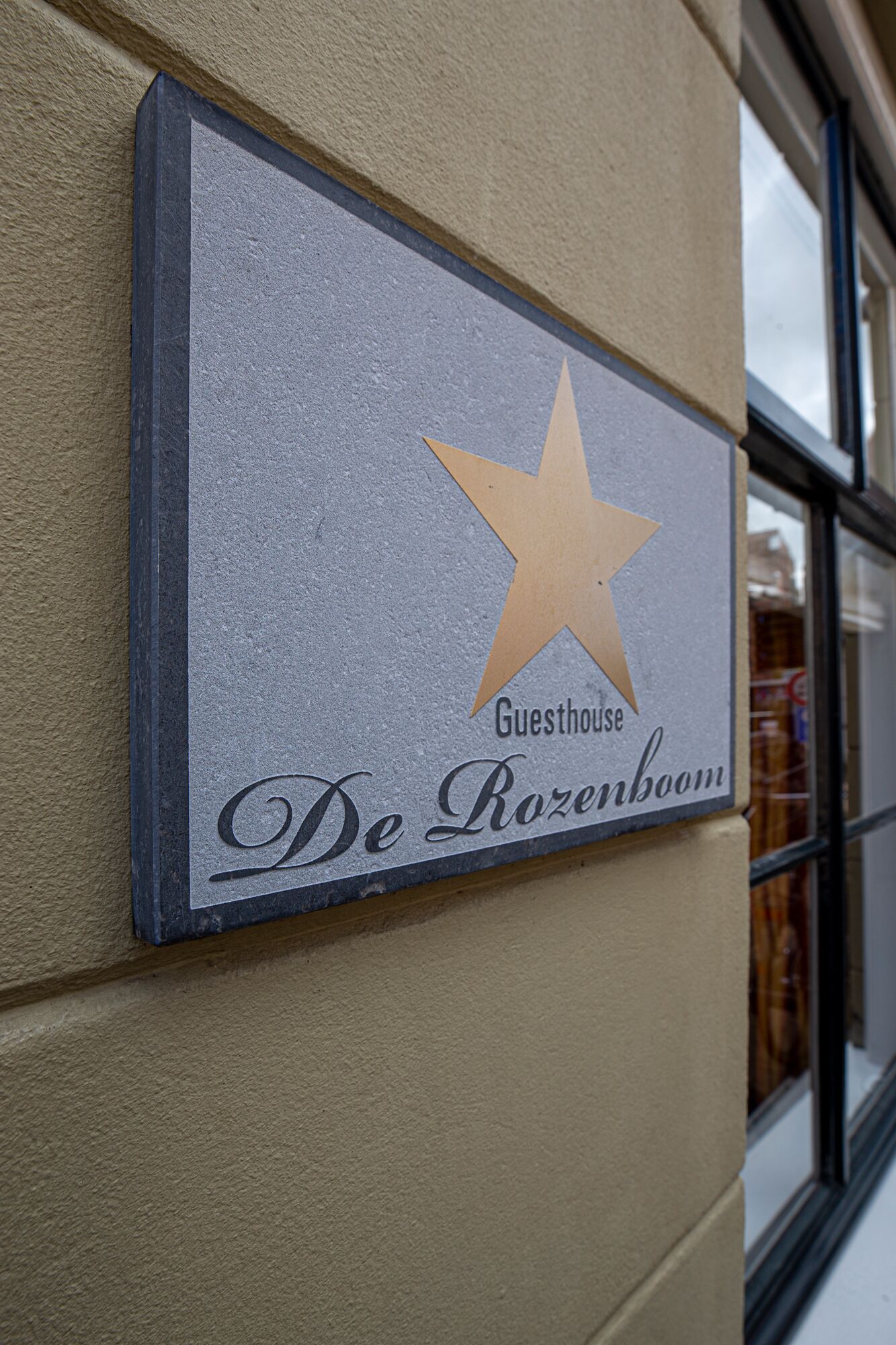 A sign for "De Rozenboom Guesthouse" with a star symbol.