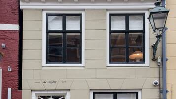 Een gebouw met twee verdiepingen, een zwarte deur, een bord waarop staat 'Anno de Snijder 1639' en een lantaarnpaal aan de rechterkant.