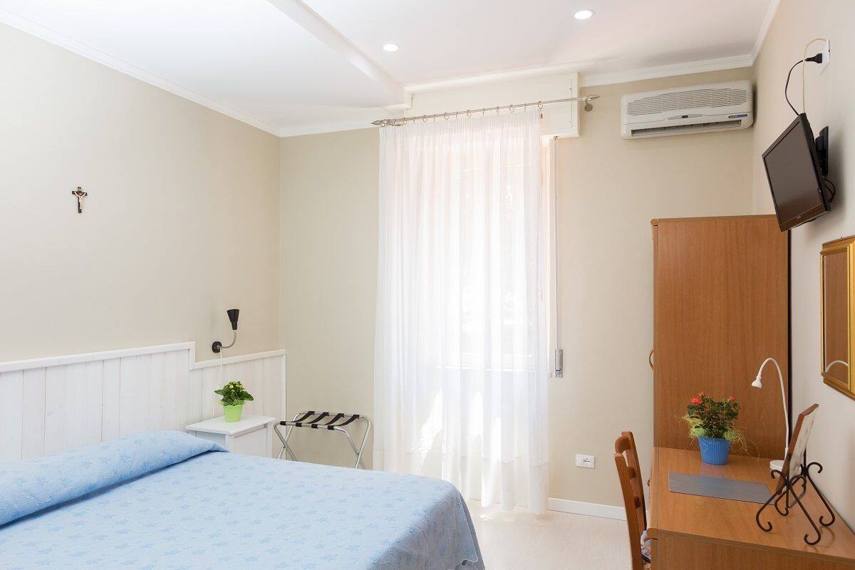 A bedroom with a bed, a desk, a chair, a TV, and a wardrobe.
