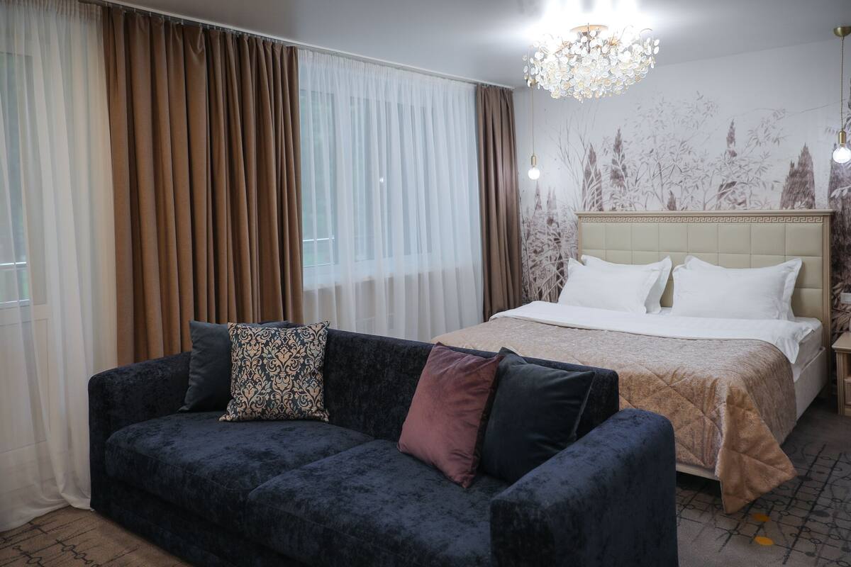 Hotellihuone, jossa on sänky, tummansininen sohva ja kattokruunu.