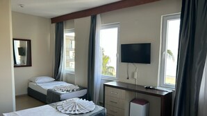 A hotel room with two beds, a desk, a TV, and a window with curtains. - Rosella Hotels (Alanya)