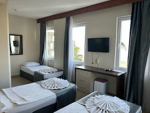 A hotel room with two beds, a desk, a TV, and a window with curtains.