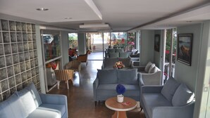 A spacious living area with multiple sofas and armchairs, a coffee table, and a view through large glass doors to the outside. - Rosella Hotels (Alanya)