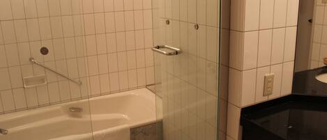 Une salle de bain avec une baignoire, une cabine de douche en verre et un plan de toilette noir avec un évier.