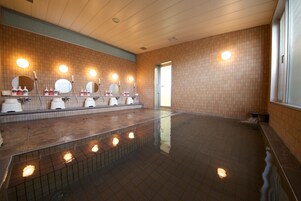 Un área de baños públicos con varios lavamanos, espejos y suelo de baldosas.