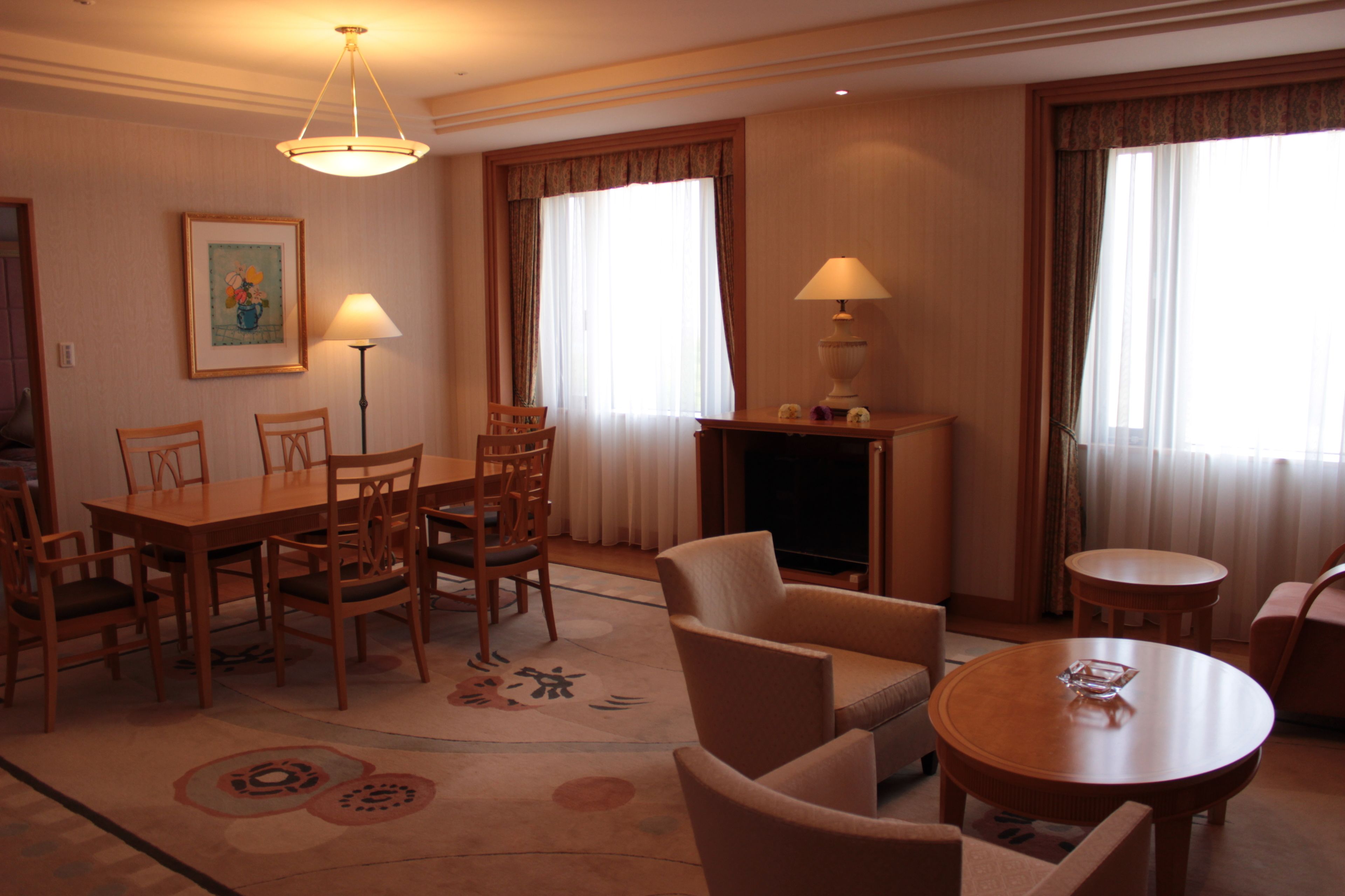 Una camera d'albergo con zona pranzo, camino e salotto con tavolo rotondo e sedie.