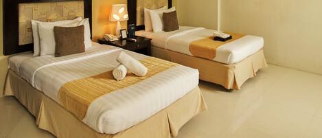 A hotel room with two beds, each with a headboard, a nightstand, a lamp, and a painting on the wall.