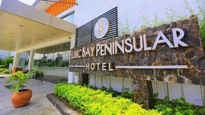 Exterior del Hotel Subic Bay Peninsula con fachada de piedra, una planta grande en maceta y una entrada moderna.