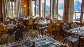Un restaurante con mobiliario de madera y amplios ventanales que ofrecen vistas a la montaña.