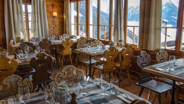 A restaurant with wooden furniture and large windows offering mountain views. - Hotel Le Grand Chalet Favre (Anniviers)