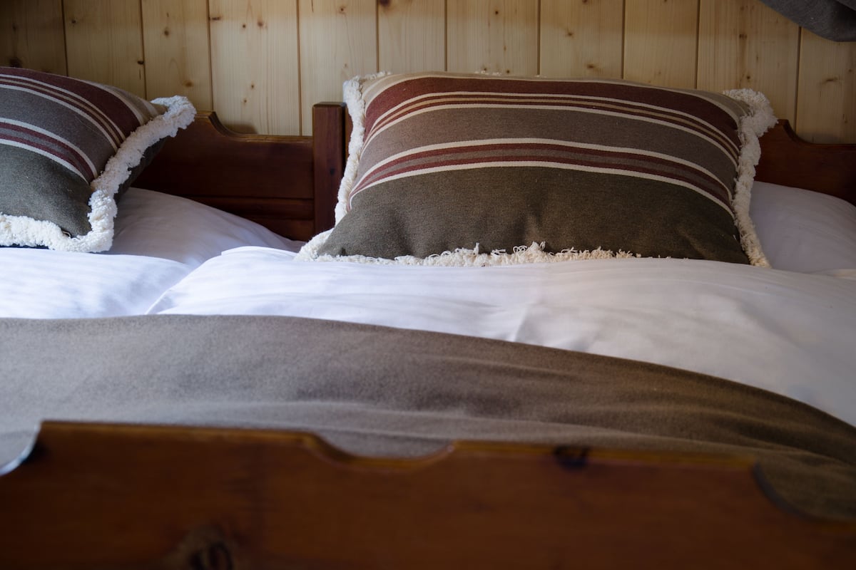 A wooden bed with two pillows and a white blanket.
