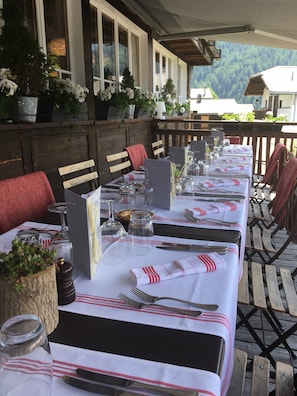 Una larga mesa de comedor cubierta con manteles blancos y rayas rojas, rodeada de sillas de madera.