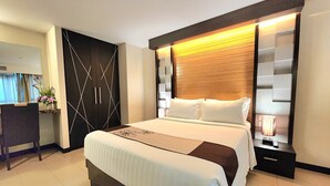 Una habitación de hotel moderna con una cama grande, un escritorio y un armario.